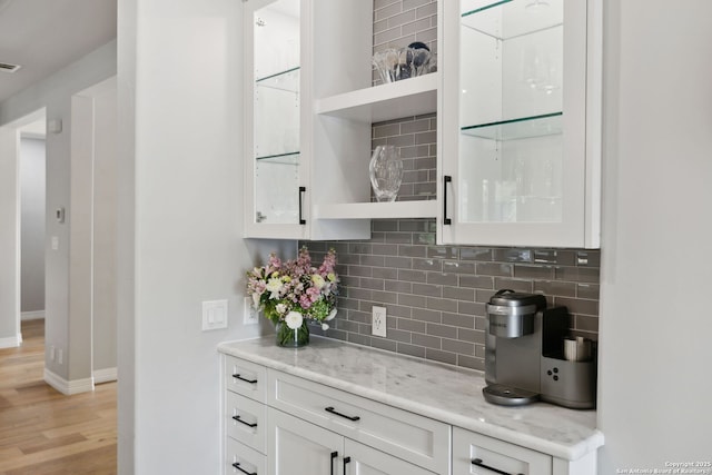 bar featuring light wood-style flooring, baseboards, and tasteful backsplash