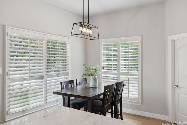 dining space featuring plenty of natural light, wood finished floors, baseboards, and a chandelier