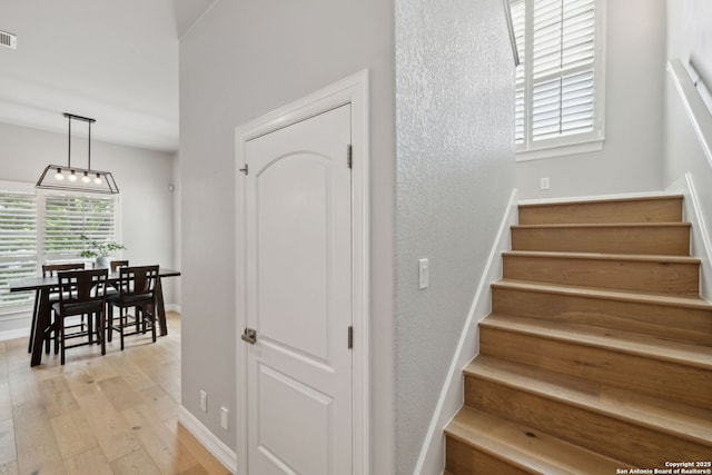 stairway with baseboards, a chandelier, wood finished floors, and visible vents