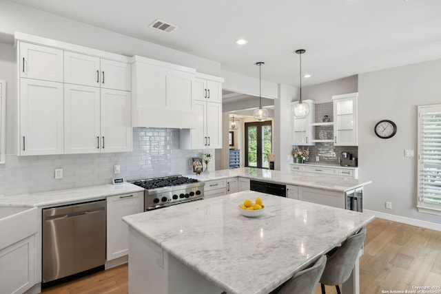 kitchen with stainless steel dishwasher, decorative backsplash, range, light wood-style flooring, and visible vents