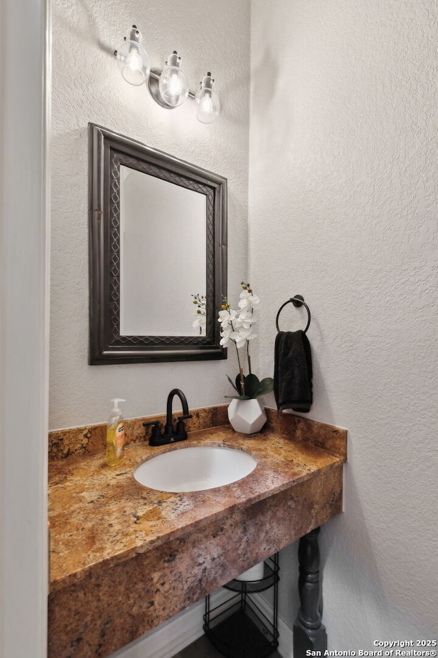 bathroom featuring a textured wall and a sink