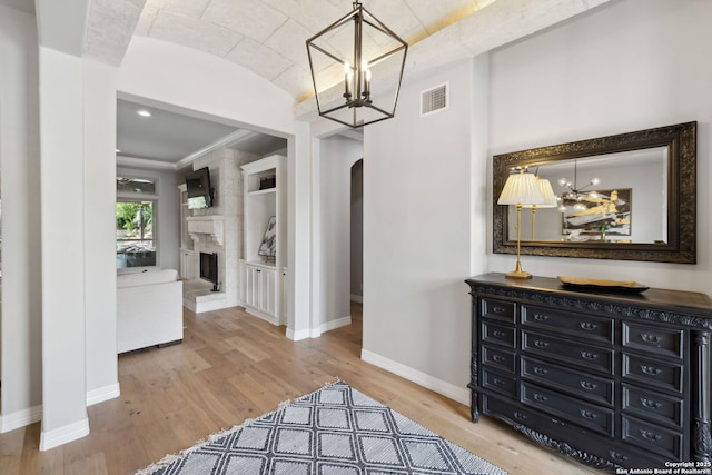 entrance foyer featuring a chandelier, arched walkways, visible vents, and wood finished floors
