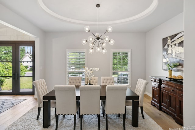 dining area with french doors, light wood-style floors, a chandelier, and a healthy amount of sunlight