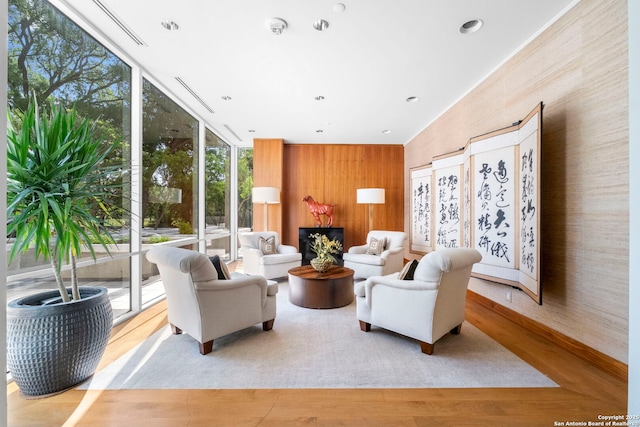 living area with expansive windows, wood walls, wood finished floors, and recessed lighting