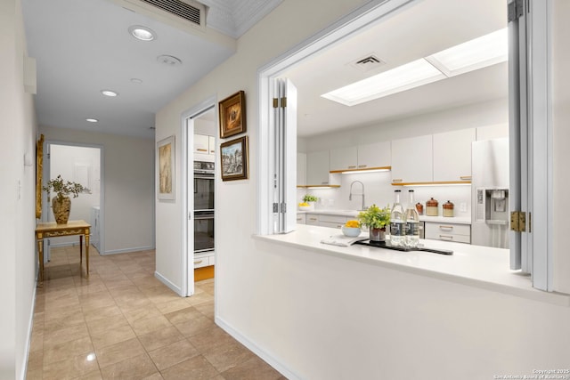 corridor featuring recessed lighting, visible vents, baseboards, and a sink
