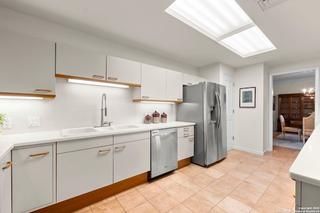 kitchen featuring a sink, tasteful backsplash, baseboards, light countertops, and appliances with stainless steel finishes