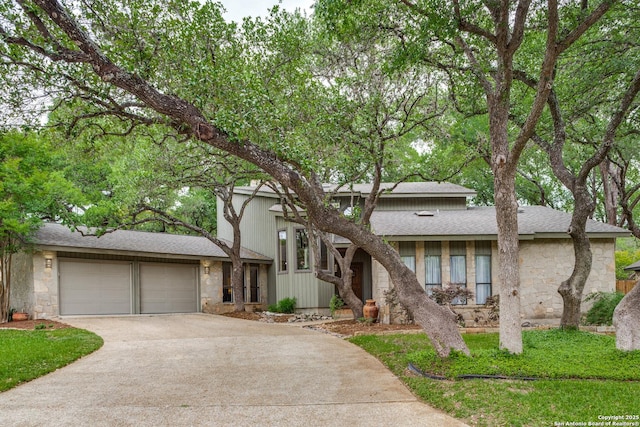 view of front of property with stone siding, an attached garage, and driveway