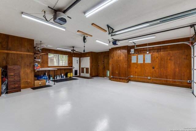 garage featuring wooden walls, electric panel, a workshop area, and a garage door opener