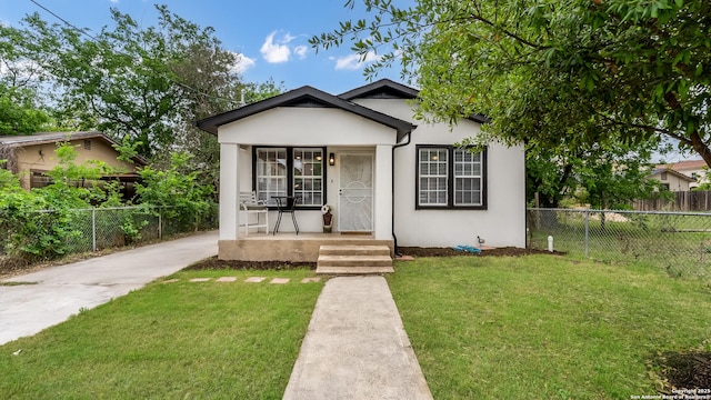 bungalow-style home with stucco siding, fence, a porch, and a front yard