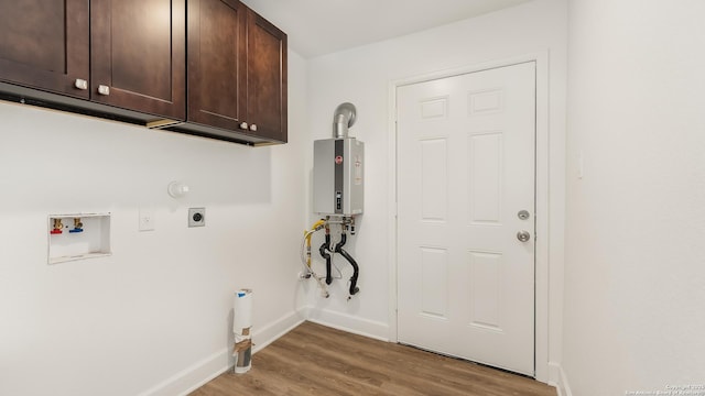 laundry room with electric dryer hookup, gas dryer hookup, light wood-type flooring, and cabinet space