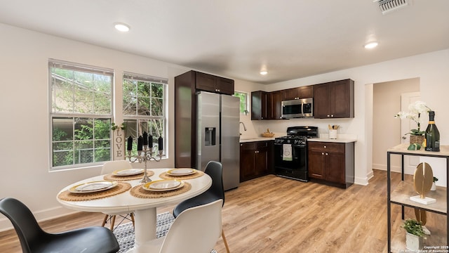 kitchen with light wood-type flooring, dark brown cabinetry, stainless steel appliances, light countertops, and visible vents