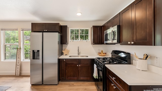 kitchen featuring appliances with stainless steel finishes, dark brown cabinets, a sink, and light countertops