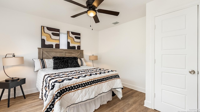 bedroom featuring visible vents, baseboards, a ceiling fan, and wood finished floors