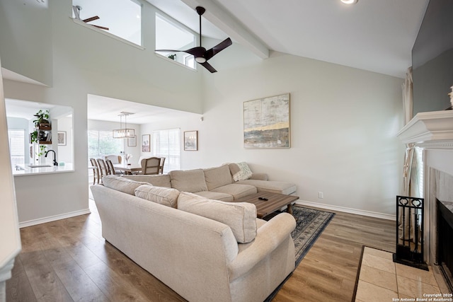 living room featuring a tiled fireplace, baseboards, ceiling fan, and wood finished floors