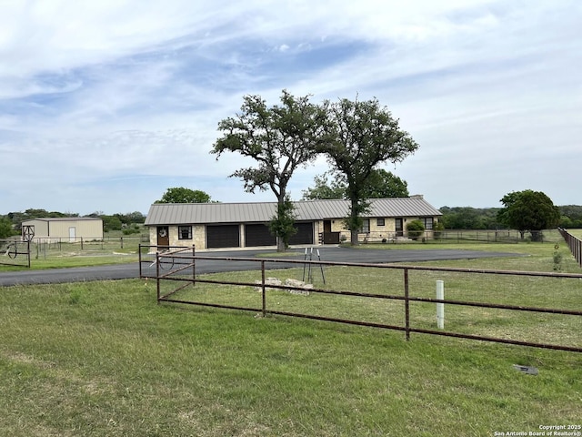 view of front facade featuring an outbuilding, metal roof, fence, a front yard, and aphalt driveway
