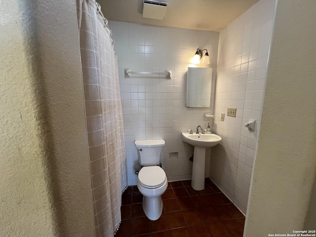 bathroom featuring tile patterned flooring, toilet, a shower with curtain, a sink, and tile walls