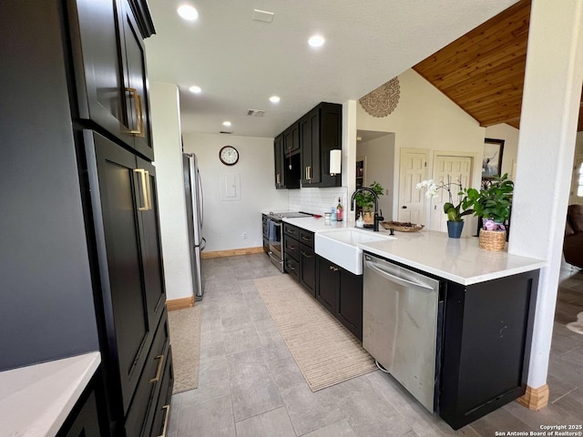 kitchen featuring light countertops, visible vents, dark cabinetry, a sink, and appliances with stainless steel finishes