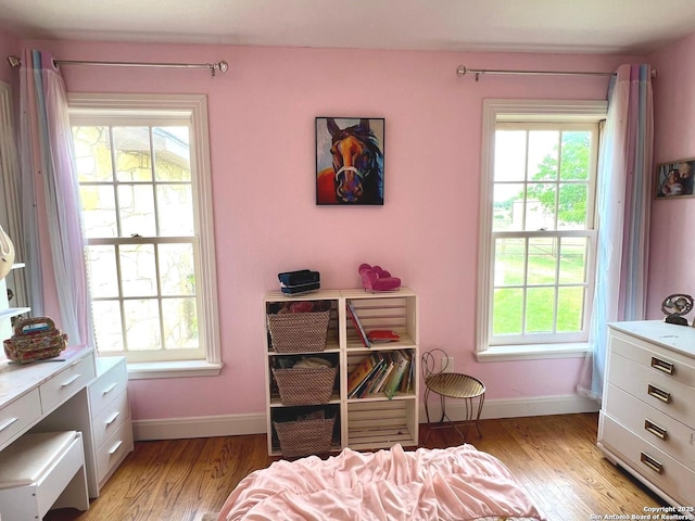 bedroom featuring light wood-style flooring, baseboards, and multiple windows