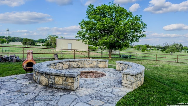 view of patio with fence, a rural view, and a fire pit