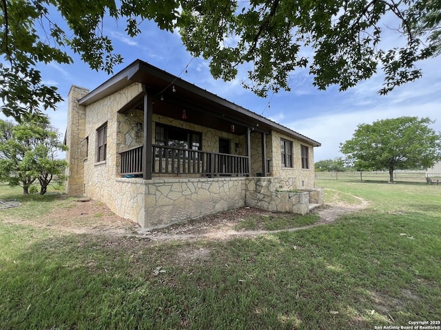 view of home's exterior featuring stone siding, a lawn, and fence