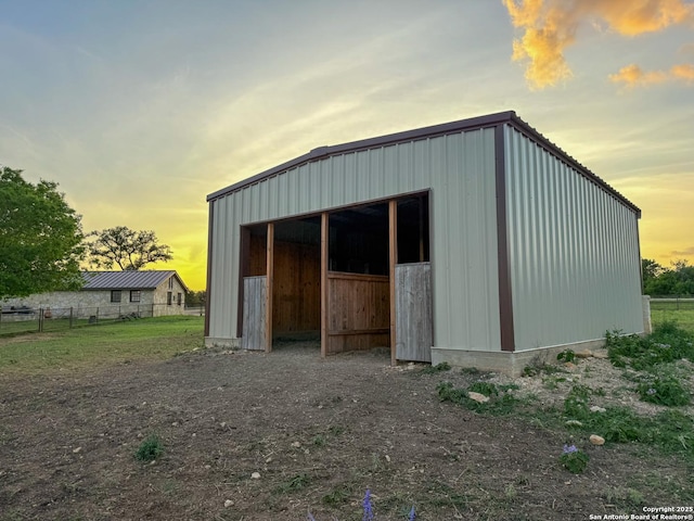 outdoor structure at dusk with fence, an outbuilding, and a pole building