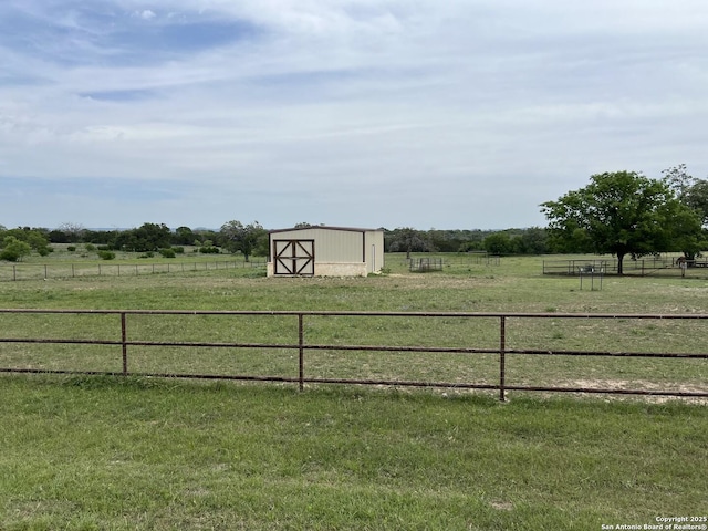 view of yard featuring fence, a rural view, and an outbuilding