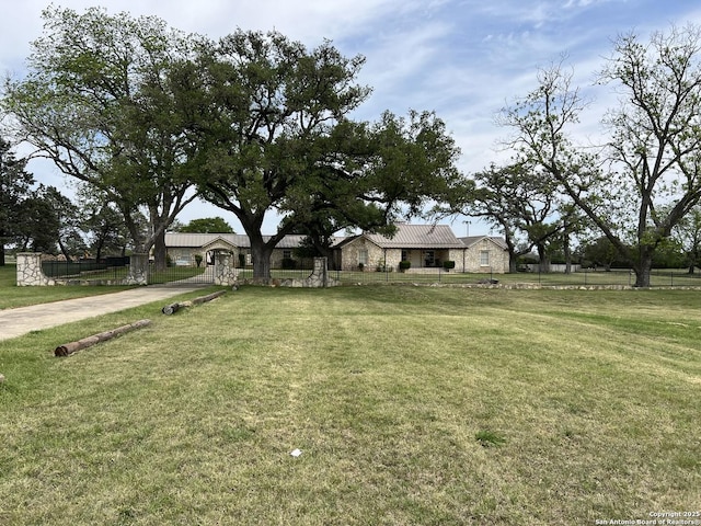 view of front of house with a front lawn, fence, stone siding, and metal roof