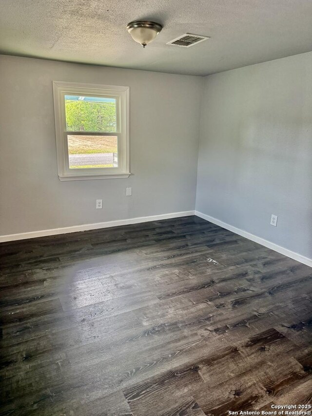 705 Short, Seguin, TX 78155 - spare room featuring dark wood finished floors, baseboards, a textured ceiling, and visible vents