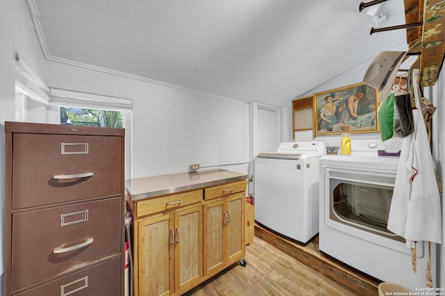 clothes washing area with light wood-style flooring, independent washer and dryer, and cabinet space