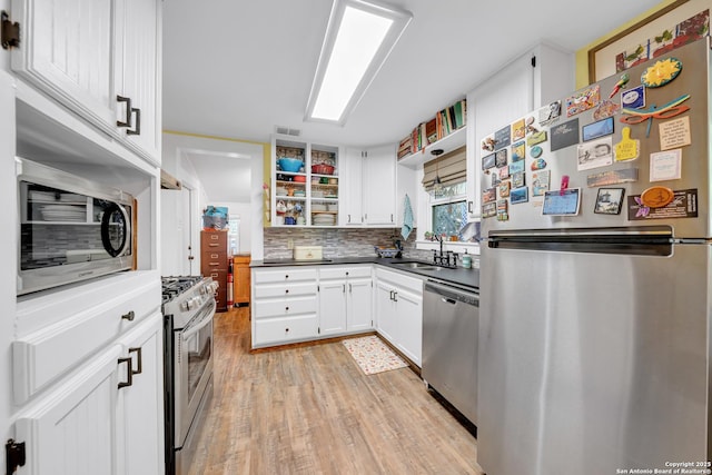 kitchen with open shelves, visible vents, a sink, light wood-style floors, and appliances with stainless steel finishes
