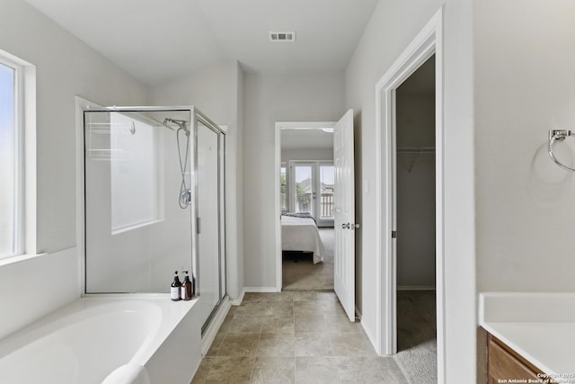 bathroom with a shower stall, visible vents, a walk in closet, a bath, and baseboards