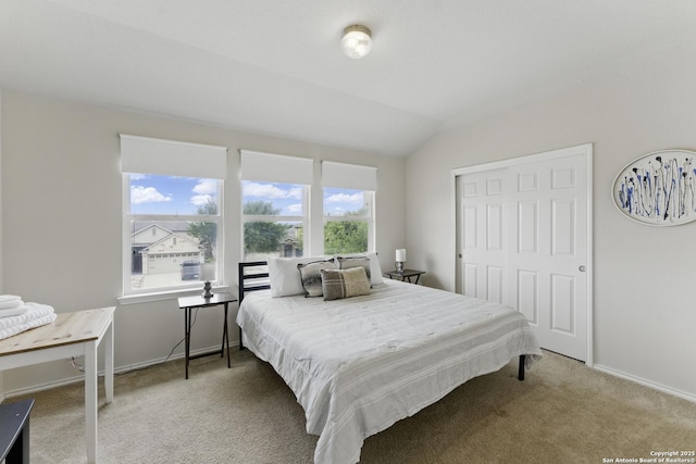 carpeted bedroom with vaulted ceiling, baseboards, and a closet