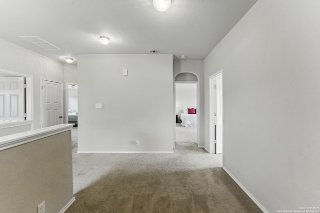 unfurnished room featuring light carpet, baseboards, visible vents, and arched walkways