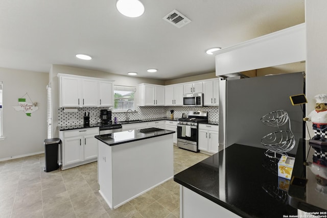 kitchen with stainless steel appliances, visible vents, a sink, and dark countertops