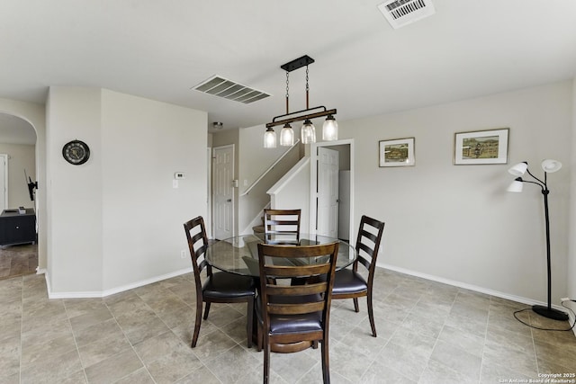 dining room featuring arched walkways, baseboards, visible vents, and stairs