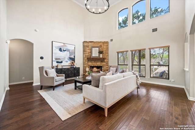 living area featuring a towering ceiling, visible vents, arched walkways, and dark wood-type flooring