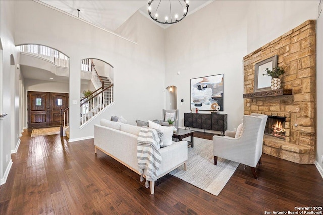 living room with hardwood / wood-style flooring, arched walkways, a notable chandelier, and stairway