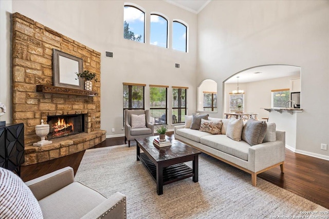 living room with arched walkways, baseboards, visible vents, wood finished floors, and ornamental molding