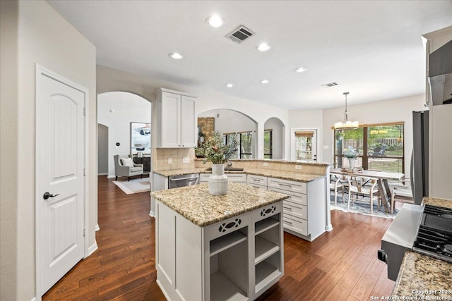 kitchen featuring stainless steel dishwasher, arched walkways, a peninsula, a notable chandelier, and visible vents