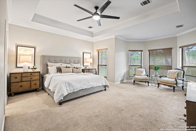 carpeted bedroom featuring a tray ceiling, visible vents, and crown molding
