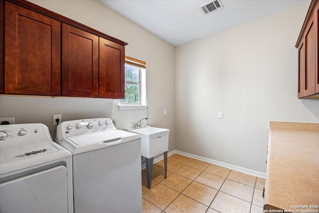 clothes washing area with light tile patterned floors, cabinet space, baseboards, visible vents, and independent washer and dryer
