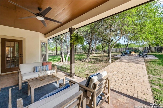 view of patio / terrace featuring a fenced backyard, a ceiling fan, and an outdoor living space with a fire pit