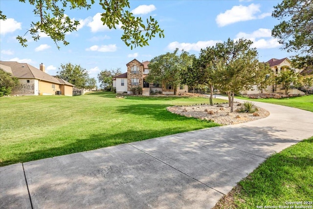 view of property's community featuring a residential view, a lawn, and driveway