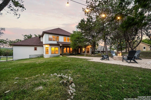 back of house featuring a fire pit, fence, a patio area, a lawn, and stucco siding