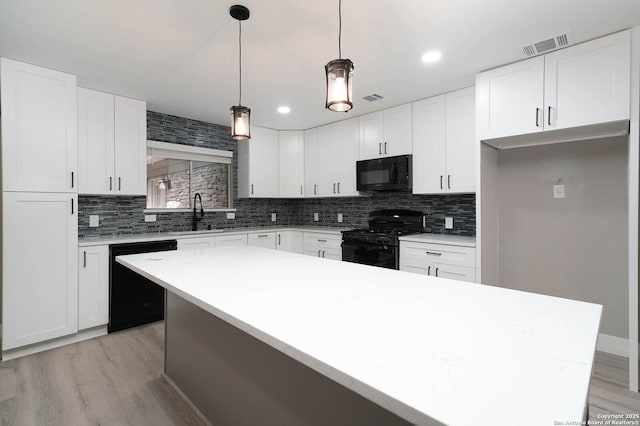 kitchen with light wood-type flooring, visible vents, backsplash, and black appliances