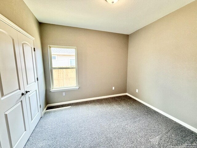 unfurnished bedroom featuring baseboards, a closet, and carpet