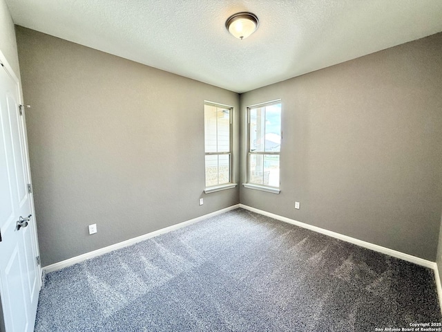 carpeted spare room featuring baseboards and a textured ceiling