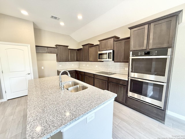 kitchen with a sink, dark brown cabinetry, stainless steel appliances, backsplash, and visible vents