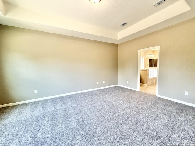 unfurnished room with baseboards, visible vents, carpet floors, and a raised ceiling