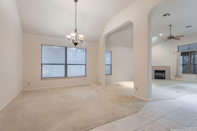 interior space with arched walkways, lofted ceiling, a healthy amount of sunlight, and a tiled fireplace